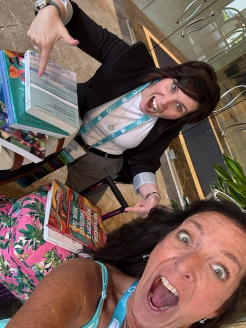 Terina pointing enthusiastically at group counseling books with Lisa looking happy